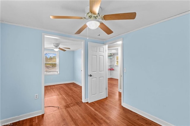 spare room featuring baseboards, wood finished floors, a ceiling fan, and crown molding
