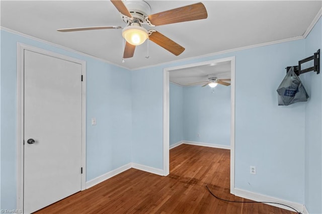 empty room featuring wood finished floors, ceiling fan, baseboards, and crown molding