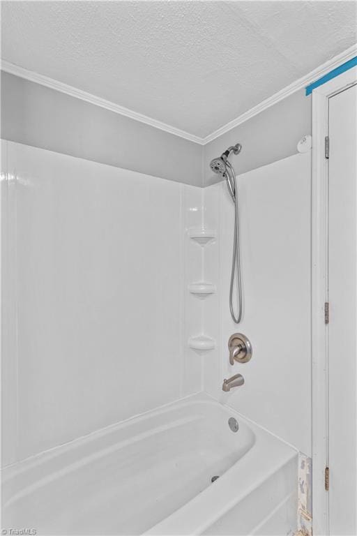bathroom with a textured ceiling, crown molding, and bathtub / shower combination