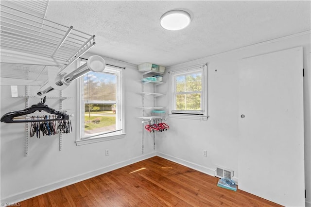 bonus room featuring a textured ceiling, wood finished floors, and baseboards