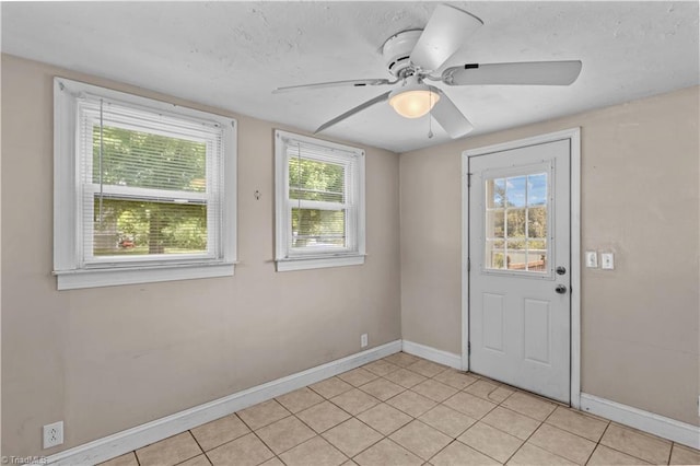 empty room with baseboards, a ceiling fan, and light tile patterned flooring