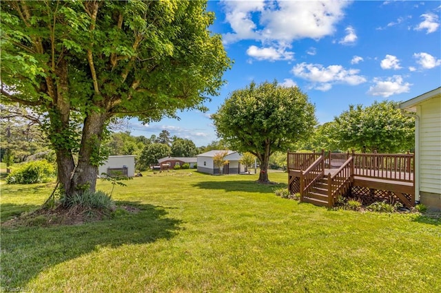 view of green lawn with a wooden deck