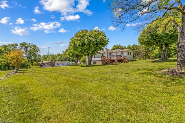 view of green lawn featuring a deck and stairs