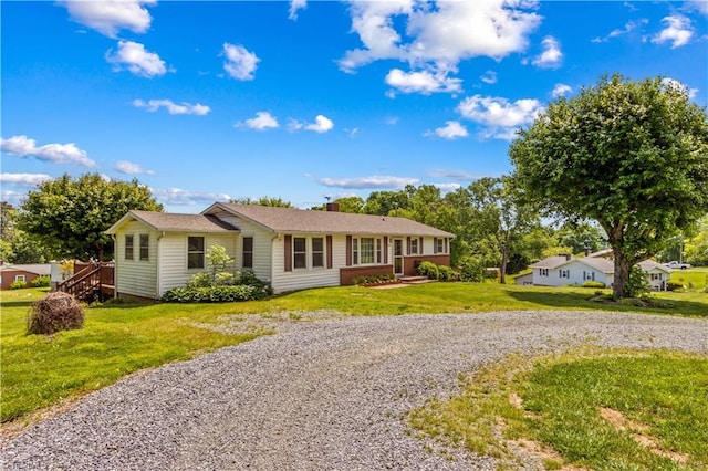 ranch-style home with driveway, a front yard, and a chimney
