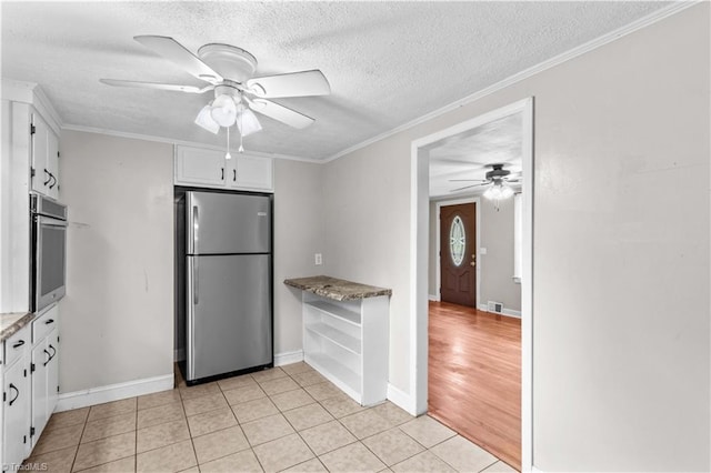 kitchen with stainless steel appliances, a ceiling fan, white cabinetry, a textured ceiling, and baseboards