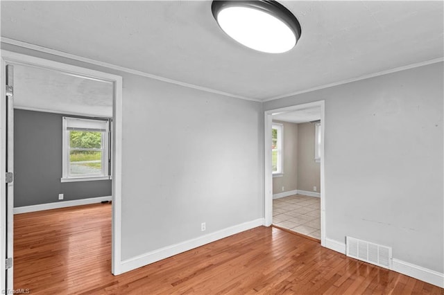 empty room featuring wood finished floors, crown molding, and baseboards