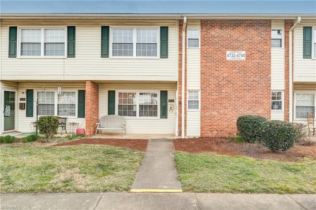 view of property featuring a front yard and brick siding