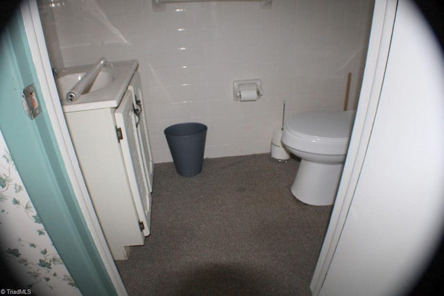 bathroom featuring vanity, tile walls, and toilet