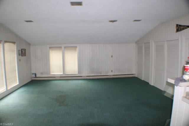 carpeted spare room featuring lofted ceiling and baseboard heating