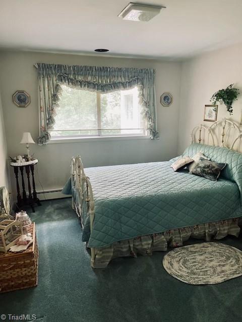 bedroom with dark carpet and baseboard heating