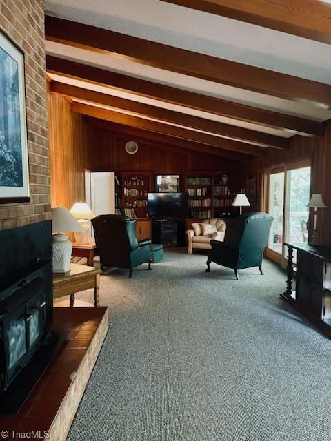 carpeted living room featuring lofted ceiling with beams and wood walls