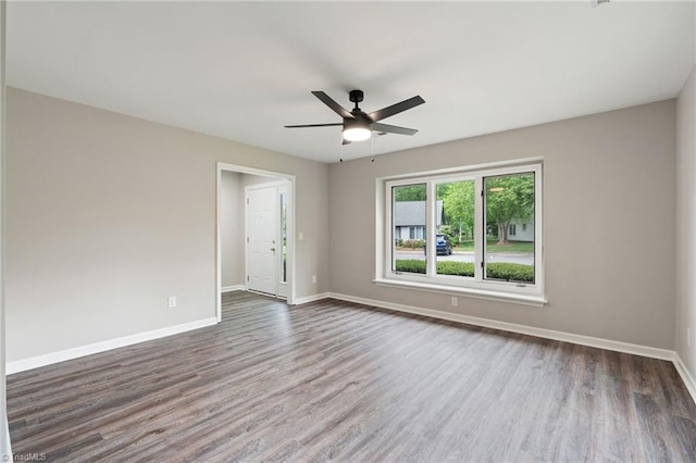 spare room featuring baseboards, a ceiling fan, and dark wood-style floors