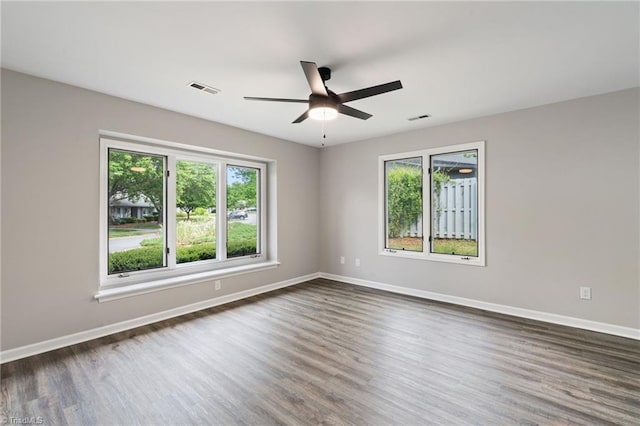 unfurnished room with a ceiling fan, dark wood-style floors, and a wealth of natural light