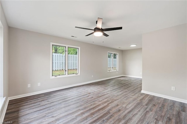 empty room with baseboards, a ceiling fan, wood finished floors, and visible vents