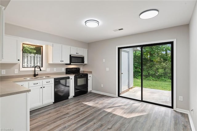kitchen featuring a sink, black appliances, light wood-style flooring, and visible vents