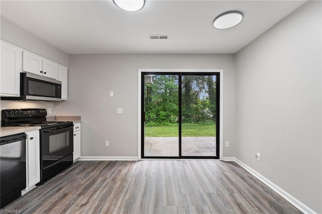 kitchen featuring visible vents, wood finished floors, light countertops, white cabinetry, and black appliances