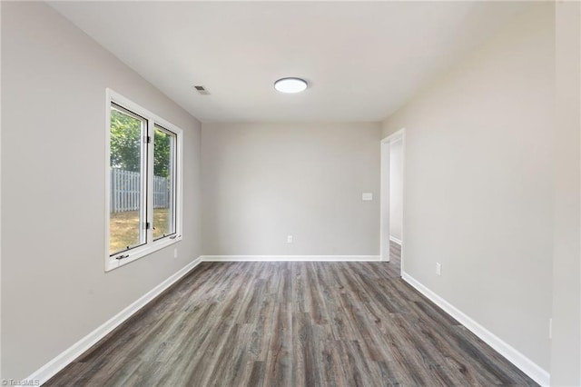 unfurnished room with dark wood-type flooring, baseboards, and visible vents