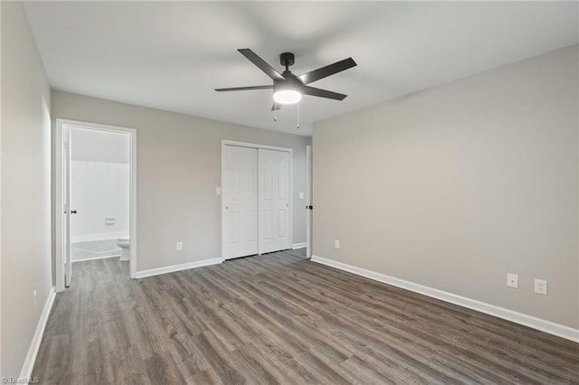 unfurnished bedroom featuring baseboards, dark wood-style floors, and a closet