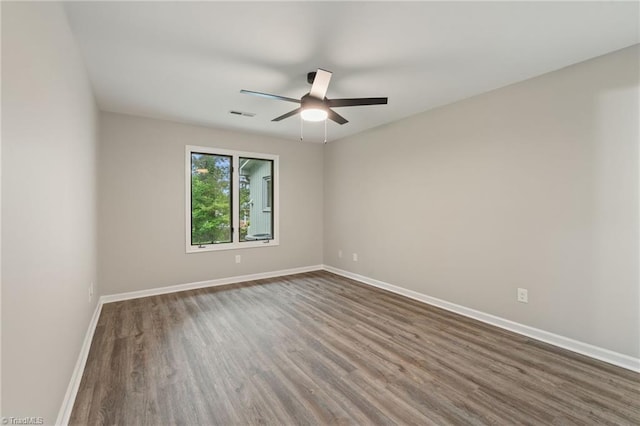 spare room with baseboards, ceiling fan, visible vents, and wood finished floors