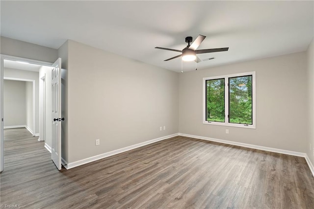unfurnished room featuring baseboards, dark wood finished floors, ceiling fan, and visible vents