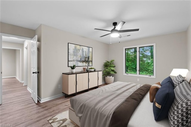 bedroom with baseboards, ceiling fan, light wood-style flooring, and visible vents