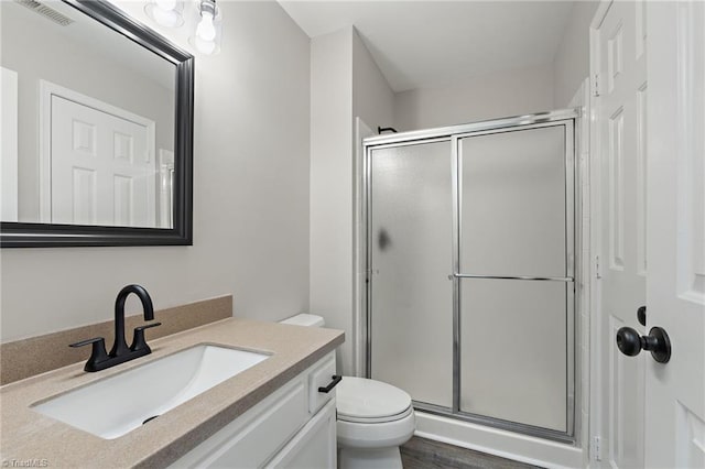 full bathroom featuring vanity, a stall shower, toilet, and visible vents
