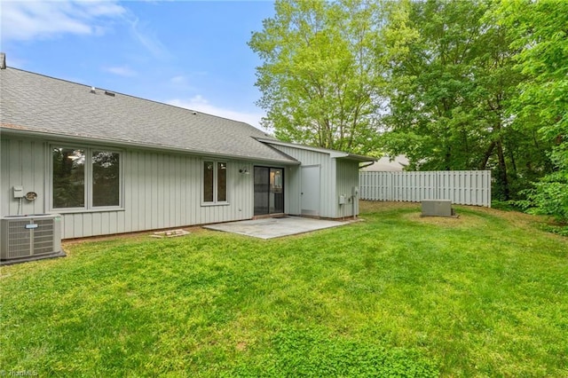 rear view of house with central AC, fence, a shingled roof, and a patio area