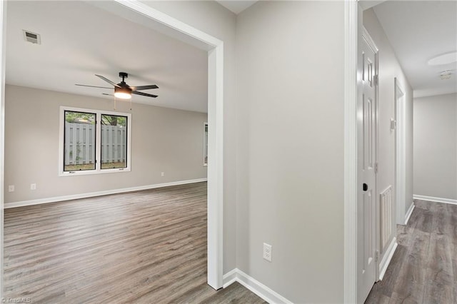 corridor featuring visible vents, baseboards, and wood finished floors