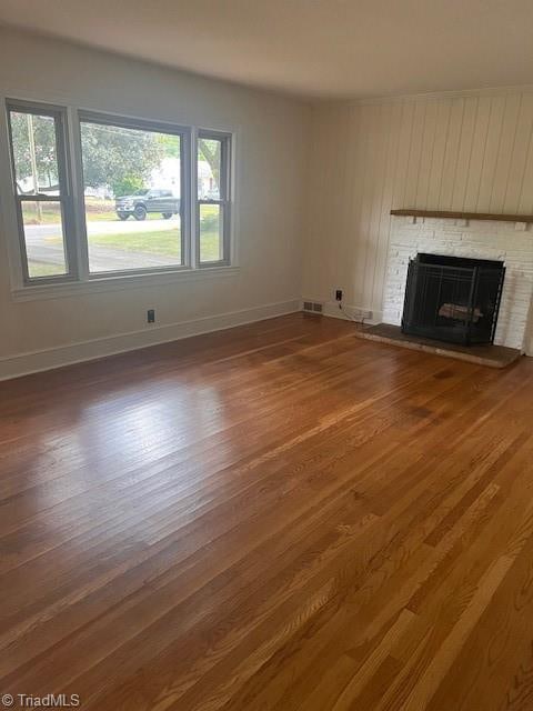 unfurnished living room featuring dark hardwood / wood-style flooring and a brick fireplace