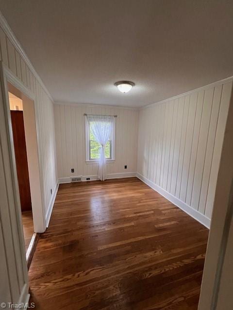 empty room with crown molding and dark hardwood / wood-style flooring