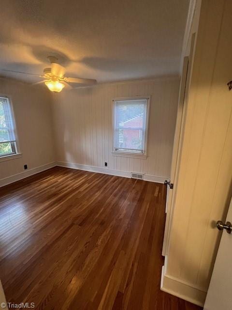 unfurnished room with a healthy amount of sunlight, ceiling fan, and dark hardwood / wood-style flooring