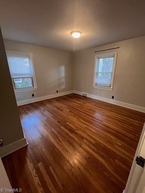 unfurnished room featuring a healthy amount of sunlight and dark hardwood / wood-style flooring