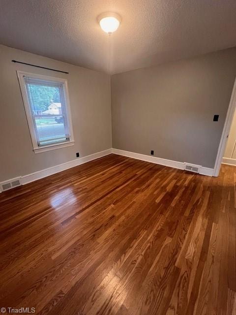 spare room featuring a textured ceiling and hardwood / wood-style flooring