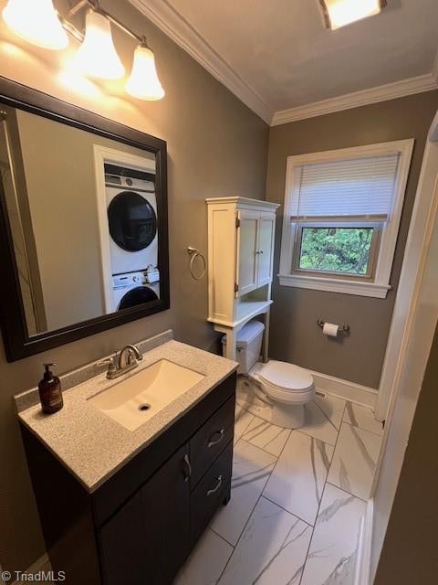 bathroom featuring vanity, stacked washer and clothes dryer, ornamental molding, and toilet