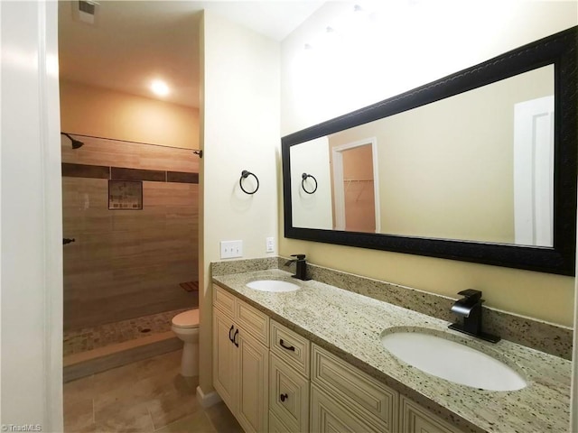 bathroom with vanity, tiled shower, toilet, and tile patterned flooring