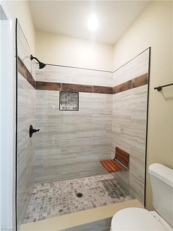 bathroom with tiled shower and toilet