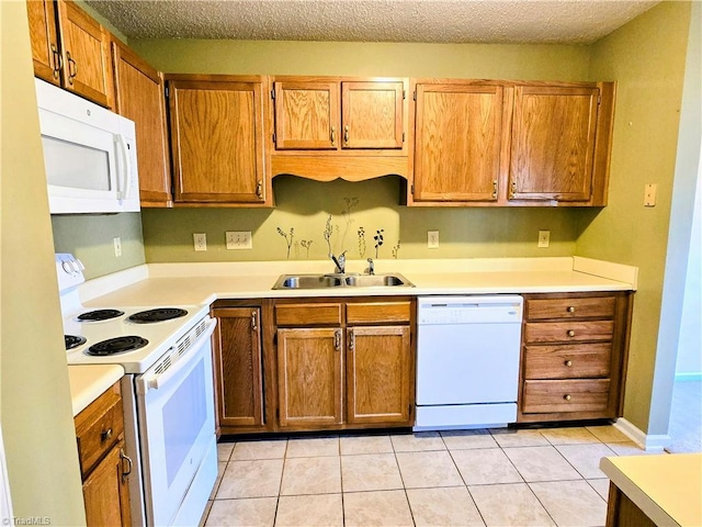 kitchen with white appliances, sink, a textured ceiling, and light tile patterned floors