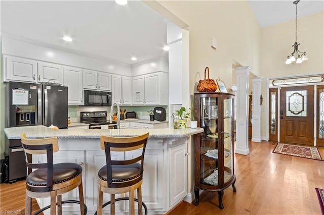 kitchen with black appliances, white cabinetry, kitchen peninsula, and light hardwood / wood-style flooring