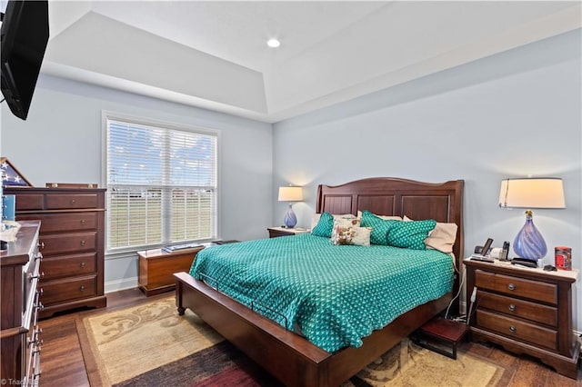 bedroom with dark hardwood / wood-style flooring and a tray ceiling