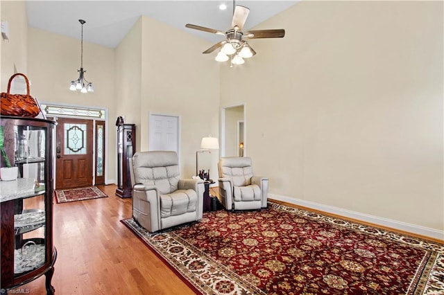 interior space with hardwood / wood-style floors, ceiling fan with notable chandelier, and high vaulted ceiling