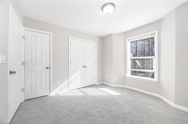 unfurnished bedroom featuring light carpet and two closets