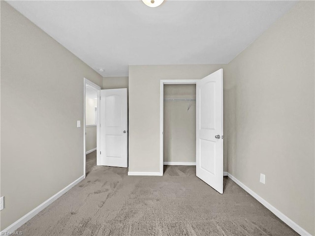 unfurnished bedroom with baseboards, carpet floors, and a closet