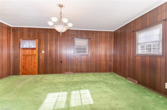 empty room with wood walls, carpet, and a chandelier