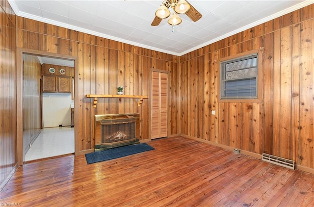 living room featuring wood walls, hardwood / wood-style floors, ceiling fan, and ornamental molding