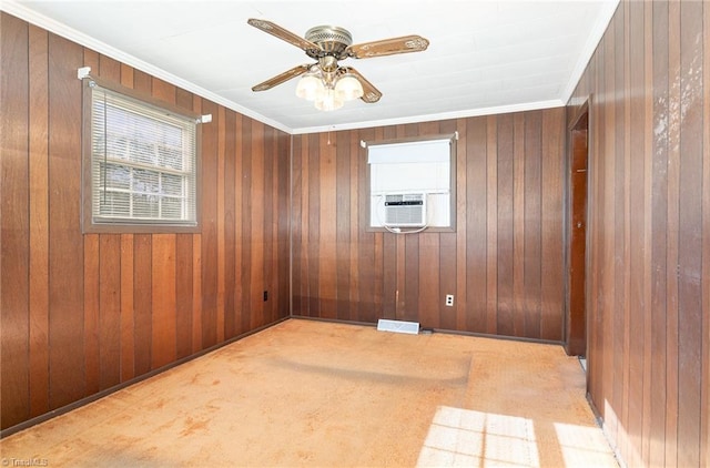 carpeted spare room featuring ceiling fan, wood walls, and ornamental molding