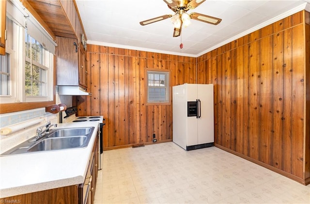 kitchen featuring a wealth of natural light, stove, wood walls, and white refrigerator with ice dispenser