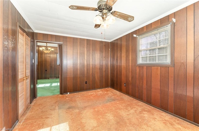 unfurnished room featuring light carpet, ceiling fan with notable chandelier, crown molding, and wooden walls