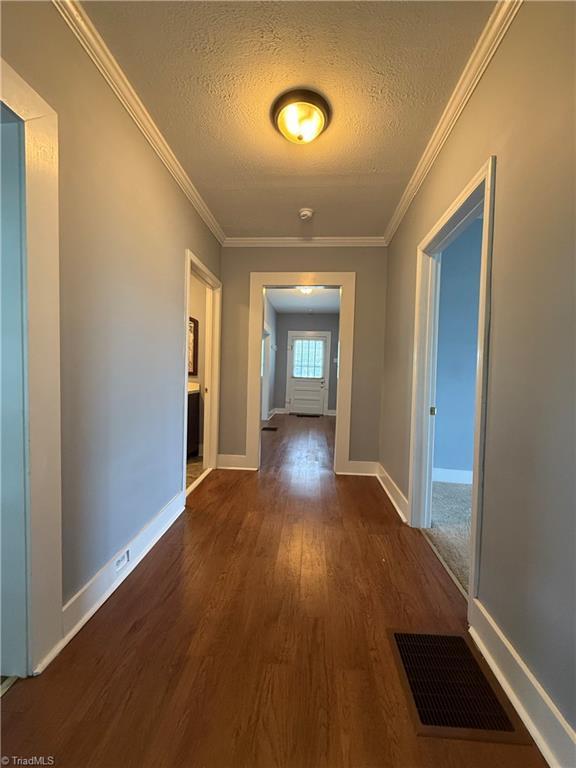 446 Durham St, Mount Airy, NC 27030 - hall featuring dark wood-type flooring, a textured ceiling, ornamental molding, and baseboards