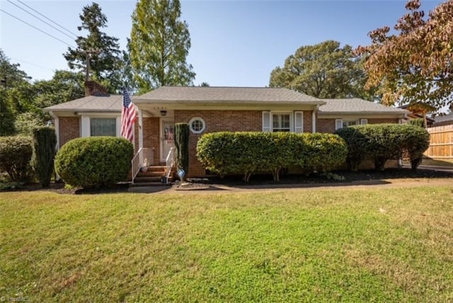 ranch-style home with brick siding, fence, and a front yard