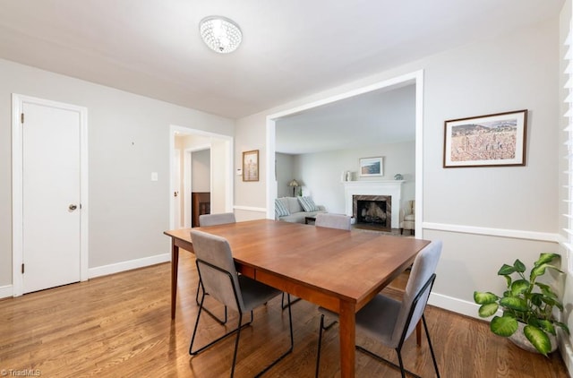 dining area with a high end fireplace and light hardwood / wood-style flooring